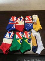 All 8 pairs of low ankle socks featuring country flags laid out flat on table, showing colorful flag designs and tags attached.