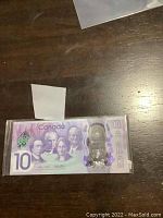 Front side of the 2017 Canada $10 polymer banknote showing portraits and denomination in protective holder.