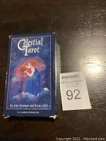 Blue Celestial Tarot card box with artwork of a woman in a celestial-themed background. The box is slightly worn but intact. Caption includes the brand U.S. Games Systems, Inc. and creators Kay Steventon and Brian Clark.