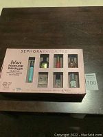 Front view of boxed deluxe Sephora perfume sampler set with eight visible mini perfume vials in a pale pink box with branding and labeling.