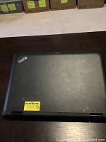 Closed Lenovo ThinkPad Yoga 11E laptop showing the black lid with ThinkPad logo and minor wear marks.