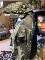 Side view of the inflated T-Rex dinosaur costume showing detailed print and inflated shape with fan working.