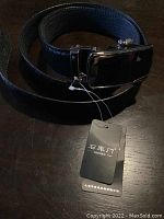 Full belt coiled showing the buckle and attached tags with Asian text.