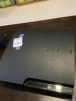 Top view of Sony PS3 console with embossed PS3 logo on top, showing general condition and surface details.