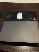 Top view of PS4 console showing the Razer logo decal and PlayStation logo on the glossy side with scratches visible