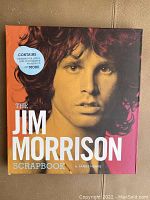 Color cover of the Jim Morrison Scrapbook showing a portrait of Jim Morrison and a sticker listing contents.