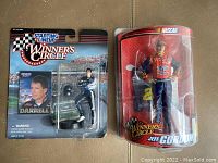 Photo showing two NASCAR figures in original packaging: Jeff Gordon Winners Circle figure in red blister pack and Darrell Waltrip Starting Lineup figure with damaged cardboard backing.