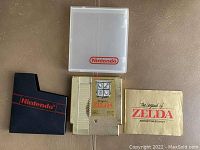 Top view of Zelda cartridge, manual, dust cover, and case on brown surface