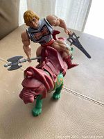 He-man riding Battle Cat, holding weapons, showing front and side view of both figures and their armor