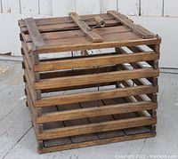 Closed view of the antique wooden egg crate showing slatted construction with hinged lid and handle on top.