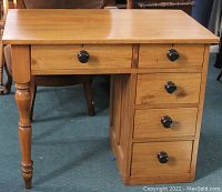 Front view of antique pine desk showing dovetailed drawers and original black knobs.