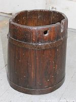 Antique wooden ship's bucket with visible wear, metal bands and one hole near the rim.