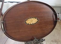 Top view of oval wooden tray showing central brass inlay and brass handles