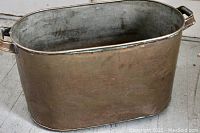 Image of a large antique copper washtub with handles on both sides showing wear and patina from age