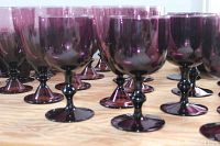 Close-up of multiple vintage purple amethyst wine glasses with smooth stems on a wooden table