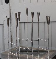 Photo of a folding metal candleholder with seven candle cups in a fan arrangement.