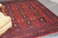 Full view of the wool kilim rug laid on concrete floor with partial view of chair