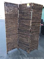 Full view of the four-panel woven room divider partition standing upright.