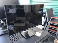 Front view of a Dell computer monitor with black frame and stand. The screen is off, reflecting surroundings.