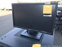 Photo of one Dell computer monitor showing front view and stand with label on screen