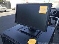 16 Dell black computer monitors stacked with one monitor shown upright displaying front view outdoors.