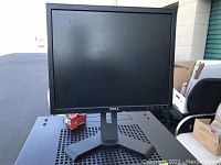 Front view of Dell computer monitor on black adjustable stand with square base, showing screen and control buttons.