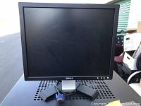 Photo of one Dell computer monitor showing front view, stand, and VGA cable connection.