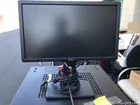 Front view of a Dell computer monitor on its stand with power and VGA cables coiled at the base.