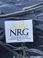 Close-up photo of NRG brand fitted disposable face rest covers in black sealed in original plastic packaging.