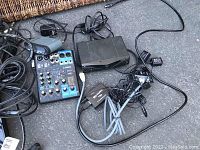 Photo showing miscellaneous electronics including Yamaha audio mixer, black box media player, and various cables and adapters.