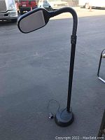 Photo showing the full black floor lamp with weighted base, flexible gooseneck, and attached power cord plugged in.