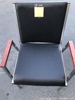 Close-up front view of garden chair showing black cushioned seat and backrest with wooden armrests and metal frame