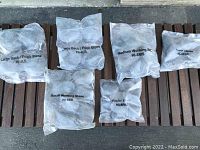 View of all hot stone bags on wooden bench rack showing labels and layout.