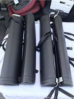 Photo showing four cylindrical black padded massage bed extension cushions arranged side-by-side with black securing straps attached.