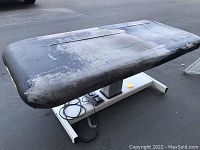 Photo showing the top surface of the massage table with heavy wear and peeling on the black upholstery.