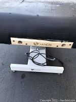 Close-up side view of Earthlite massage table's electrical base showing Earthlite branding and electric cords