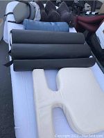 Top view of mixed lot of cushions on white backdrop showing cylindrical bolsters, breast pillow, and other cushions.