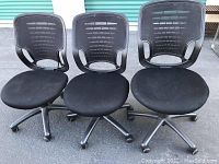Photo showing three black adjustable office chairs with mesh backs, no armrests, and wheels.