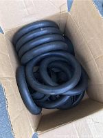 Five sets of black foam-covered Rogue gymnastic rings with straps inside a cardboard box, showing the rings stacked together with straps visible underneath.