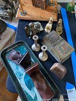 Photo showing the brass candlesticks, wooden bookends with animal carvings, copper cowbell, painted decorative box, and brass angel figurines arranged together.