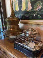 Three chafing dishes shown: large ornate metal round chafing dish with pierced lid and stand; silverplated rectangular chafing dish with lid and glass insert; Anchor Hocking chafing dish with Fire King glass insert