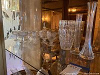 Photo of decorative glass lot including 4 cut-glass glasses, clear glass cream and sugar set, and 3 clear glass vases of various shapes and patterns