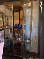 Front view of cabinet with both glass doors open revealing three glass shelves and mirrored back