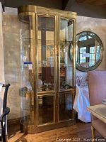 Full front view of brass and glass display cabinet installed in room