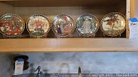 Shelf display of five collectible decorative plates with Russian fairytale scenes.