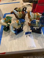 Collection of six enameled horse figurines arranged on a tabletop, showing the various colors and detailing on the horses and their bases.