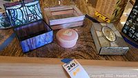 All four decorative boxes on counter showing varied stained glass patterns and porcelain box