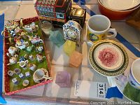 Overview of assorted mini collectibles including vintage Hershey chocolate tin truck, Delft clock, porcelain cups, and glass dreidels.