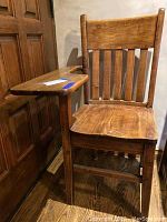 Photo showing vintage wooden school desk with slatted backrest and attached desktop. Visible scratches and wear on wood.
