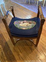 Full image showing the stool's wooden frame, legs, and embroidered seat cushion with the swan motif.